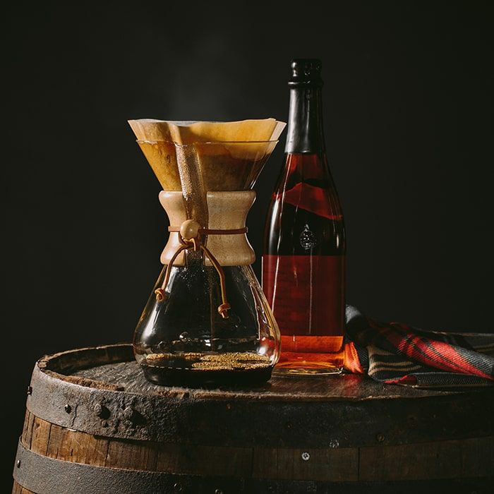 Coffee Bean Direct Highlander Grogg -- pourover alongside bottle of liquor resting on a barrel